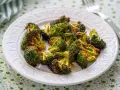 Brocoli en airfryer, crujiente y dorado, servido en un plato blanco con un mantel verde.