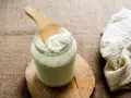 Une cuillère en bois prélève du lait fermenté d'un bocal. Idéal pour savoir que faire avec du lait fermenté.