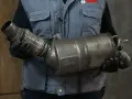 Mechanik w rękawiczkach trzyma zużyty element układu wydechowego, prawdopodobnie po problemach z wypalaniem DPF.