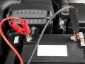 Jumper cables connected to a car battery. Learn how long to leave jumper cables on for a successful jump start.