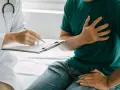 Lekarz spisuje dokumentację pacjentowi, który skarży się na ból w klatce piersiowej, co może wpłynąć na jego renta chorobowa.