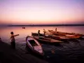 Vue d'ensemble de bateaux amarrés sur un fleuve au crépuscule, avec des silhouettes humaines sur la rive. Ces photos grand angle capturent la sérénité du moment.