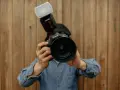 Fotograf trzyma aparat Canon z lampą błyskową. Liczba przewodnia lampy błyskowej jest kluczowa dla uzyskania idealnego oświetlenia.