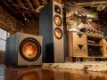 Idealne ustawienie subwoofera i głośników w industrialnym salonie. Ciemne kolumny i subwoofer z miedzianymi membranami tworzą stylowy zestaw audio.