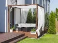 Drewniana pergola z białymi zasłonami to idealne miejsce na tarasie. Zasłony powieszone na drewnianej konstrukcji tworzą przytulną atmosferę.