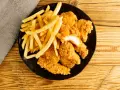 Assiette de nuggets maison dorés et croustillants avec des frites, sur fond de bois.
