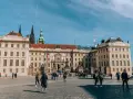 Tłum turystów spaceruje po dziedzińcu przed imponującym zamkiem na Hradczanach.