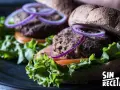Dos deliciosas hamburguesas de lentejas con lechuga fresca, tomate y aros de cebolla morada, listas para disfrutar.