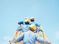 Trabajadores con cascos amarillos suben una escalera naranja contra un cielo azul claro. Podría ser una escena de cesión ilegal de trabajadores.