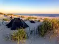 Namiot i rower na plaży, idealne miejsce na biwakowanie na dziko. Wschód słońca nad morzem.
