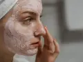 Mujer con mascarilla rosa en la cara, aprendiendo como exfoliar la cara para una piel radiante.