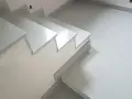 Nowoczesne schody z aglomarmuru w jasnym kolorze, idealne do minimalistycznych wnętrz.