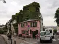 Urokliwa ulica na Montmartre z różową kawiarnią La Maison Rose i budynkiem porośniętym bluszczem.