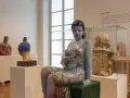 Ceramiczna rzeźba kobiety w kwiecistej sukni, dzieło inspirowane twórczością Olgi Niewskiej, prezentowana w muzeum.
