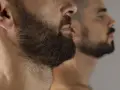 Primer plano de un hombre con barba oscura y tupida, reflejado en un espejo. La imagen captura la decisión de dejar crecer la barba.