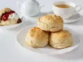 Goldbraune Scones, ein Klassiker zum Tee. Sie sind kleine, süße Gebäckstücke, die oft mit Marmelade und Sahne serviert werden.