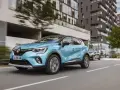 Un Renault Captur azul circula por una ciudad moderna. Es un híbrido no enchufable, eficiente y elegante.