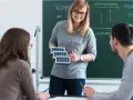 Lehrerin erklärt Schülern, wie man Berufsschullehrer wird, mit Solarzellen-Modell.