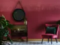Eleganckie wnętrze w odcieniu **kolor burgundowy**. Aksamitny fotel, lustro i stylowa komoda tworzą przytulną atmosferę.