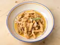 Un piatto di ciceri e tria, pasta fresca con ceci e sfoglie fritte, guarnito con rosmarino.