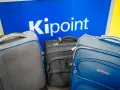 Three suitcases in front of a blue sign with "Kipoint" in white letters.