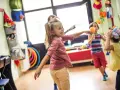 Dzieci tańczą i bawią się w sali pełnej zabawek. Czy to są gordonki? Radość i ruch!