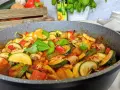 Pyszne leczo z kurczakiem w dużym garnku, pełne cukinii, papryki i pomidorów, ozdobione świeżą bazylią.