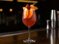 Ett glas med röd cava sangria, garnerat med apelsinskivor, jordgubbe och persika.