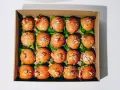 Pudełko z dwudziestoma mini burgerami na liściach sałaty, posypane sezamem i ozdobione patyczkami.