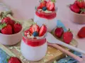 Zwei Gläser mit cremigem Joghurt und Erdbeersoße, garniert mit frischen Erdbeeren und Blaubeeren. Ein schneller Nachtisch mit Erdbeeren, der Lust auf mehr macht.
