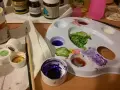 Paleta z farbami i pędzel, idealne do malowania gliny samoutwardzalnej. Kolory na palecie to zielony, fioletowy, czerwony i żółty.