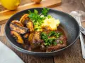 Herzhaftes Osso Buco, eine **beinscheibe italienisch** zubereitet, serviert mit cremigem Kartoffelpüree und gerösteten Kartoffelspalten.