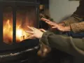 Manos calentándose frente a una chimenea con llamas danzantes. Los tubos de aire de la chimenea ayudan a distribuir el calor.