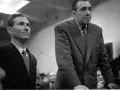 Deux hommes en costume, dont Gustave Dominici, se tiennent debout dans une salle.