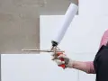 Ręka w rękawicy trzyma pistolet do pianki montażowej. Zastanawiasz się, ile schnie pianka montażowa?