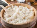 Idealny ryż do sushi, gotowy do przygotowania. Drewniana miska i łyżka sugerują tradycyjny sposób na to, jak ugotować ryż do sushi.