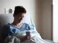 Kobieta w szpitalnym łóżku, zmagająca się z chorobą Gravesa-Basedowa, trzyma kubek.