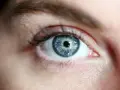 Occhio azzurro intenso, con iride dettagliata che riflette la luce. La sua trasparenza evoca il **vitrea significato** di profondità e purezza.