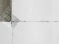 Fragment ocieplenia styropianowego na ścianie. Siatka zbrojeniowa i beton widoczne w lewym górnym rogu. Elewacja w trakcie prac.