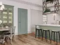 Elegancka kuchnia z wyspą w kolorze szałwiowym, przeszkloną witryną i drewnianą podłogą.