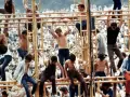 Tłum ludzi na festiwalu, niektórzy wspinają się na konstrukcję. To właśnie woodstock co to za wydarzenie?