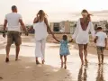 Rodzina spaceruje po plaży, trzymając się za ręce. To idealny przykład na udaną wycieczkę fakultatywną, pełną słońca i morskiej bryzy.