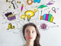 Mujer pensativa con ideas brillantes: bombillas, tesoro, llaves, lápiz, cerebro, gráficos y aviones de papel, todo son cosas para escribir.