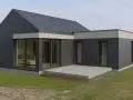 Nowoczesny domek z płyt, z dużymi przeszkleniami i płaskim dachem, otoczony zielenią.