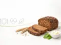 Chleb razowy z ziarnami, obok kłosów i masła. Zastanawiasz się, ile kcal ma chleb razowy? To zdrowy wybór!