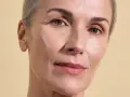 Visage d'une femme aux cheveux gris, peau lumineuse et hydratée, suggérant l'efficacité des peptides pour une peau éclatante.