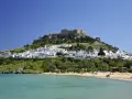 Piękna pogoda na Rodos w maju. Białe domki Lindos i akropol na wzgórzu nad turkusowym morzem.