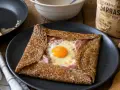 Une galette de sarrasin de grand-mère marmiton, garnie de jambon, fromage et œuf au plat. Un délice simple et réconfortant.