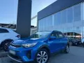 Błękitny Kia Stonic 2023 zaparkowany przed salonem samochodowym. Obok stoi biały SUV.