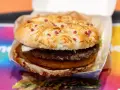 Pyszny burger drwala z podwójnym mięsem, chrupiącym plackiem ziemniaczanym i bułką posypaną serem i kawałkami boczku.